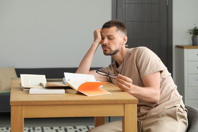 Photo of Sleepy man studying at wooden table indoors