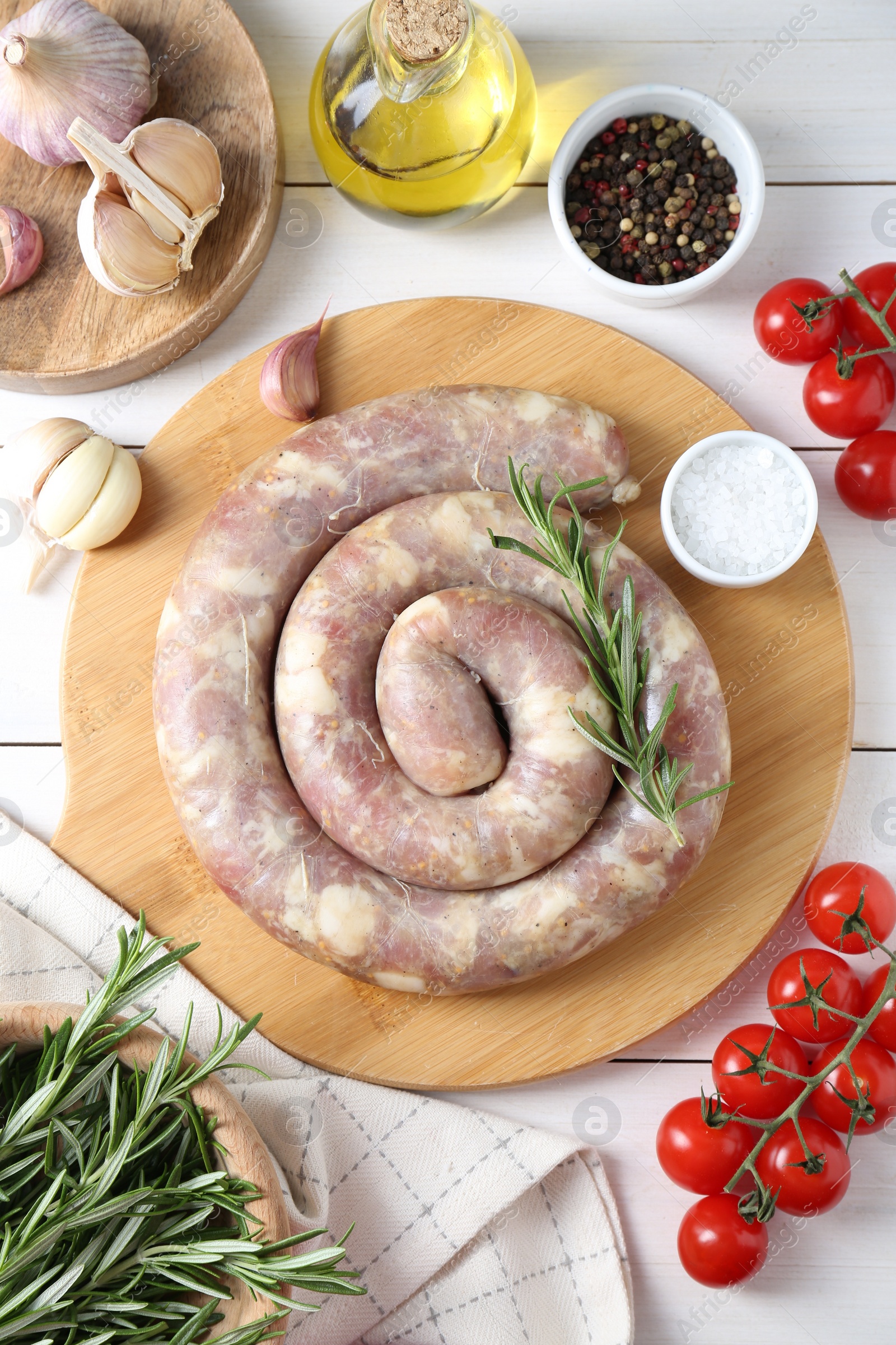 Photo of Raw homemade sausage, spices and other products on white wooden table, flat lay