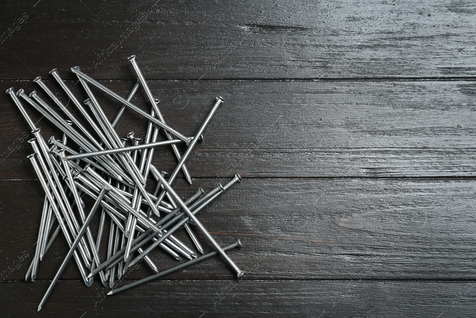 Photo of Many metal nails on wooden background, flat lay. Space for text