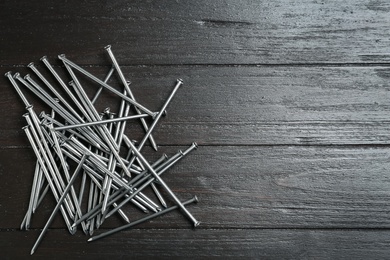 Photo of Many metal nails on wooden background, flat lay. Space for text