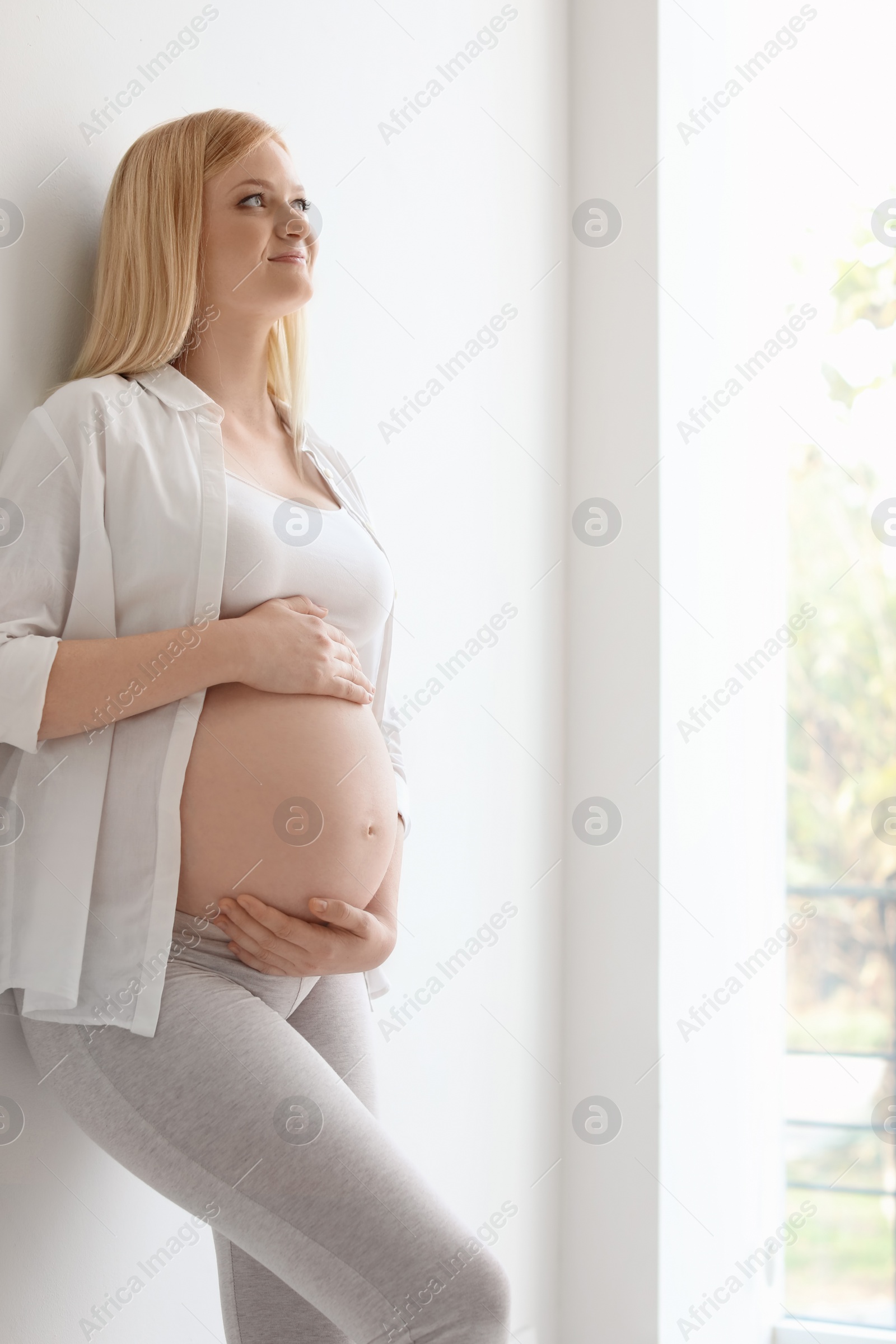 Photo of Portrait of beautiful pregnant woman near light wall