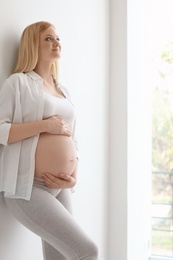 Photo of Portrait of beautiful pregnant woman near light wall