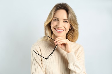 Photo of Portrait of happy young woman with beautiful blonde hair and charming smile on light background