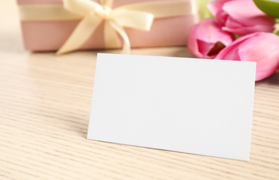 Image of Blank card with space for text, beautiful tulips and gift on wooden table