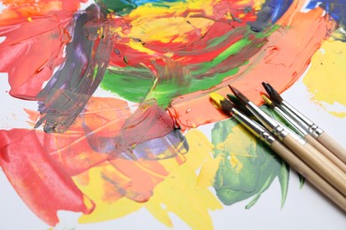 Photo of Set of brushes with different paints on artwork. Space for text