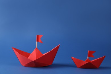 Photo of Handmade red paper boats with flags on blue background. Origami art