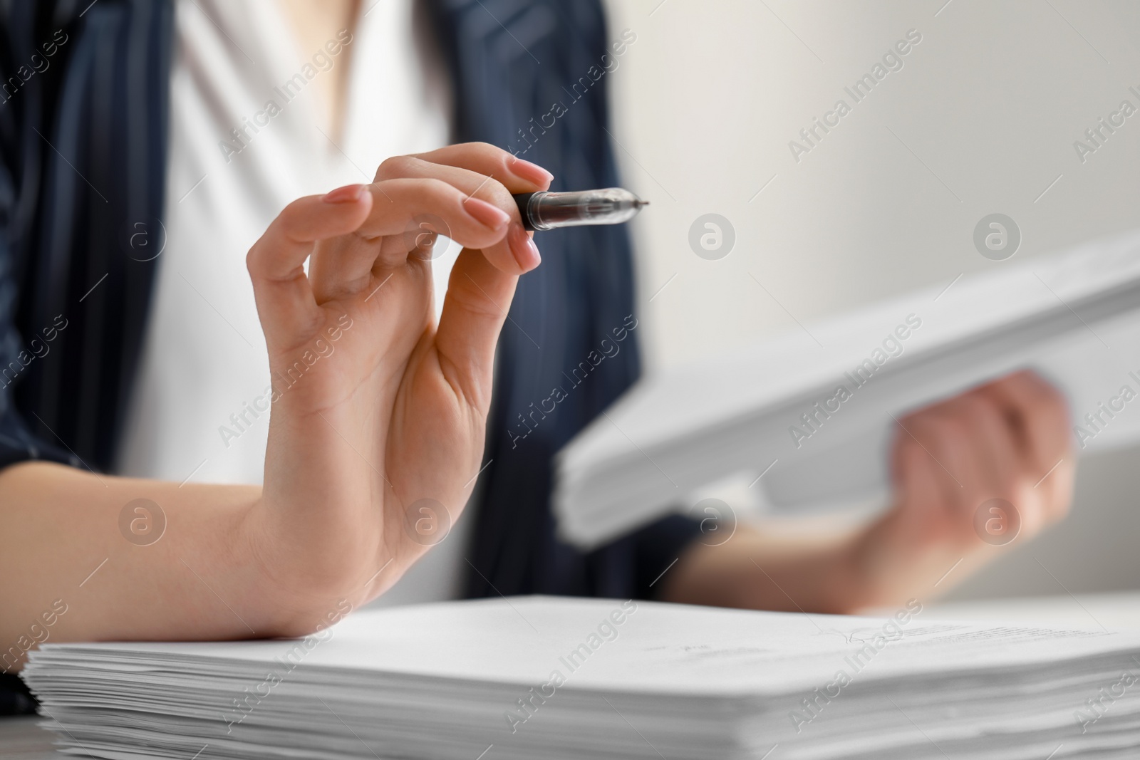 Photo of Woman holding pen and reading documents at table in office, closeup. Space for text