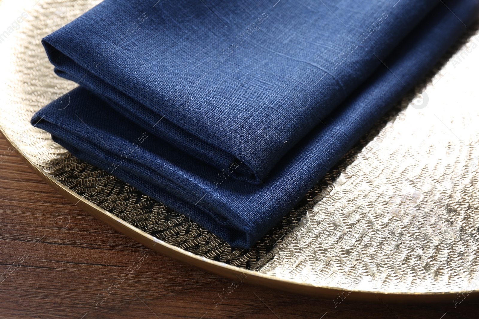 Photo of Tray with blue kitchen napkins on wooden table, closeup