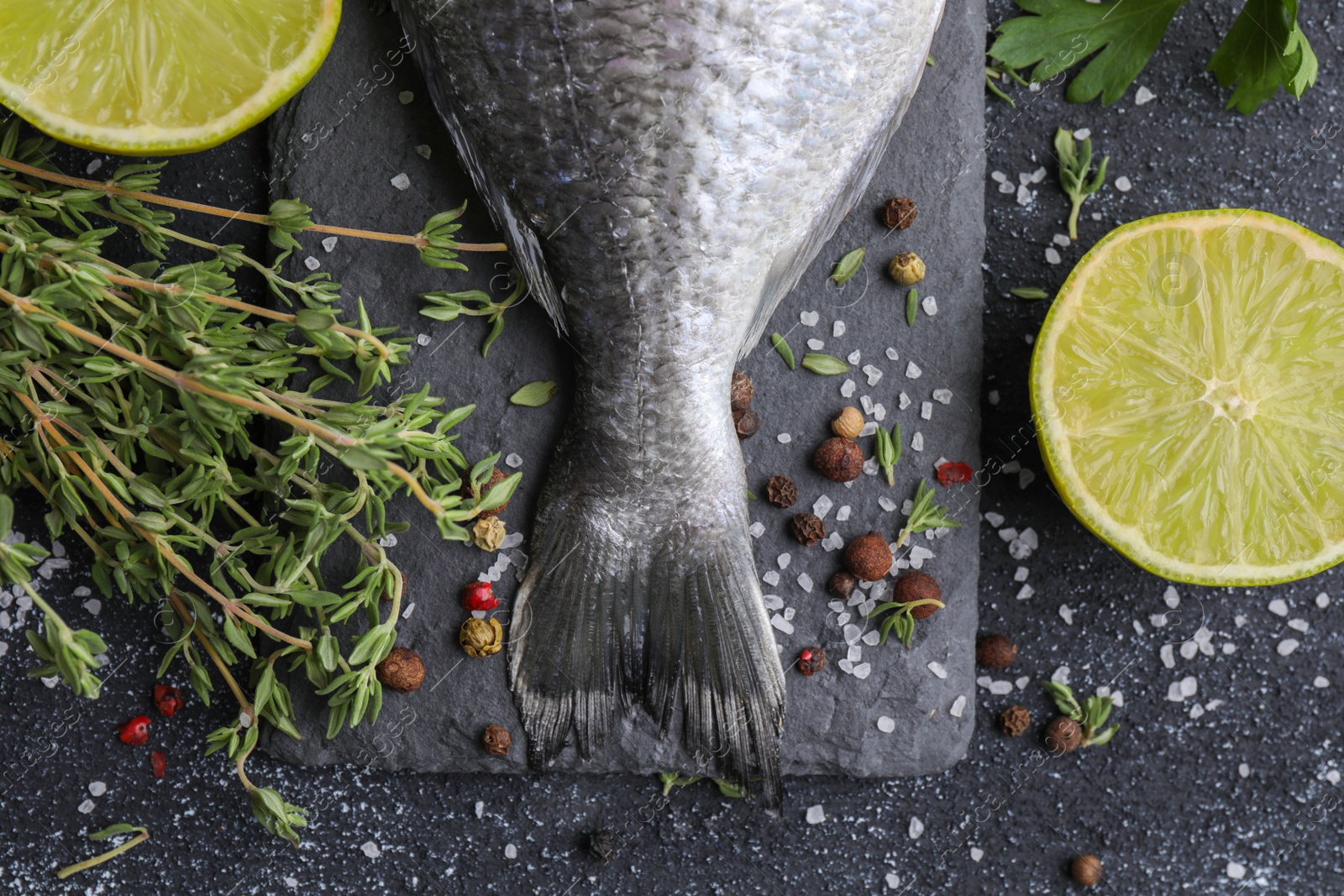 Photo of Fresh dorado fish and ingredients on black table, flat lay