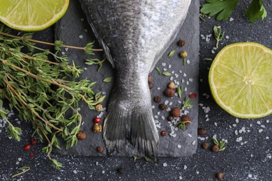 Fresh dorado fish and ingredients on black table, flat lay