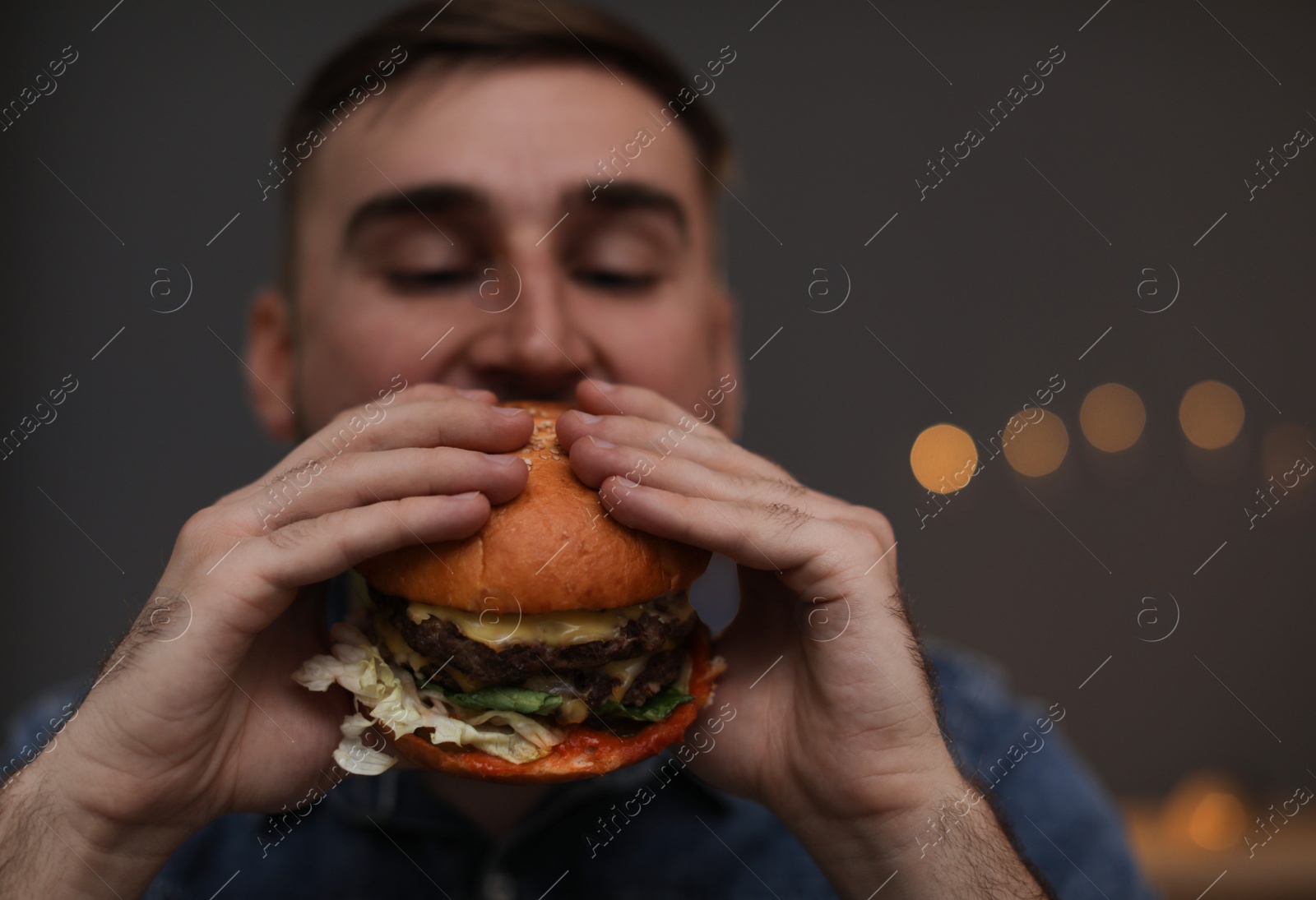 Photo of Young man eating tasty burger in cafe