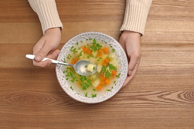 Sick woman eating fresh homemade soup to cure flu at table, top view
