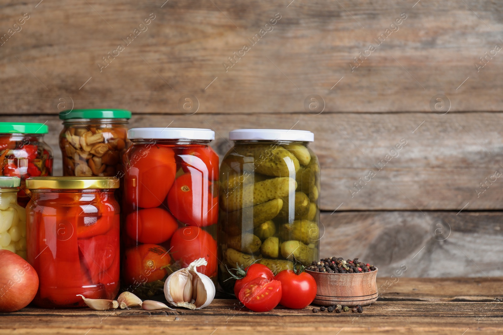 Photo of Glass jars with different pickled vegetables on wooden table