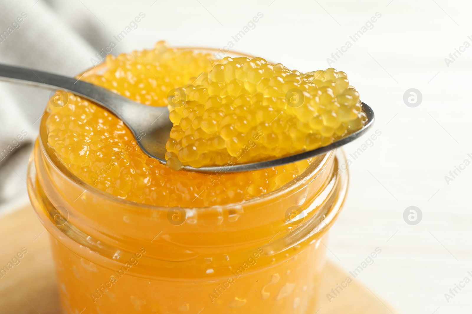 Photo of Taking fresh pike caviar from glass jar on white table, closeup