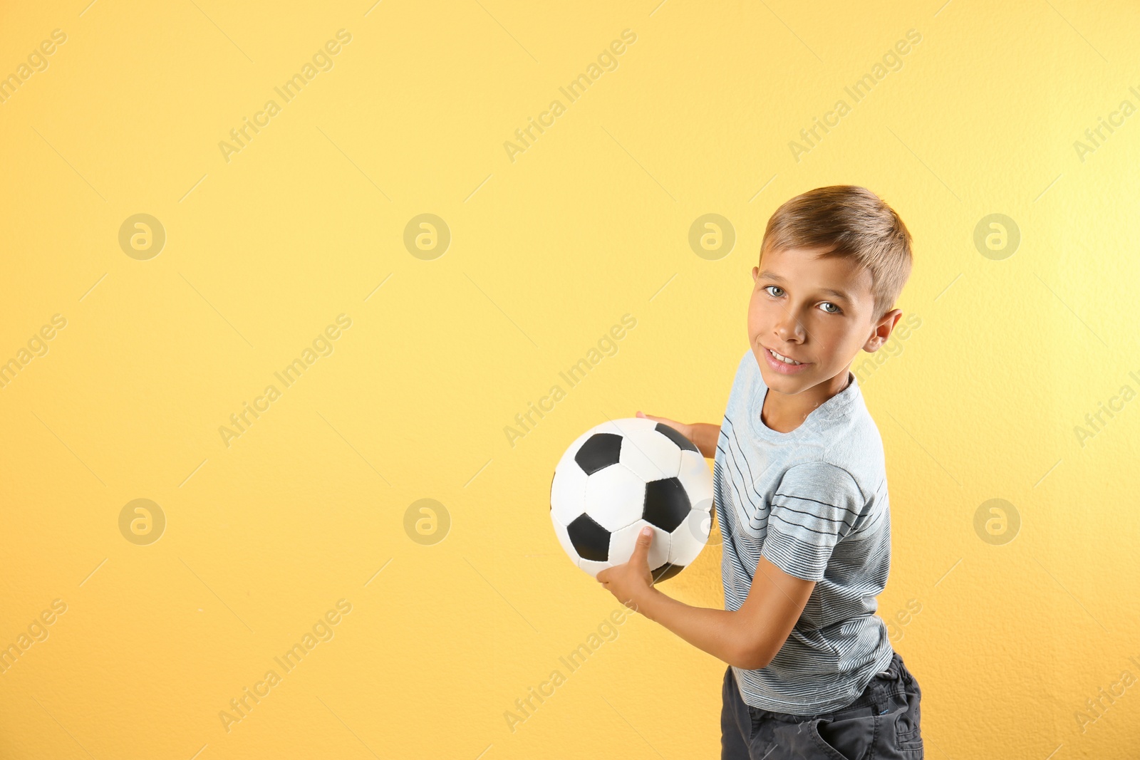 Photo of Adorable little boy with soccer ball on color background