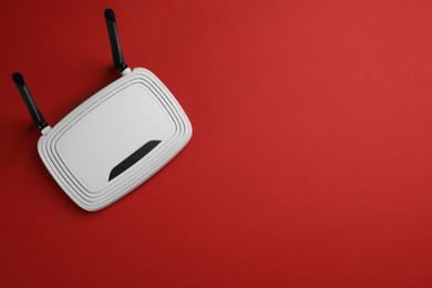 Photo of Modern Wi-Fi router on red background, top view. Space for text