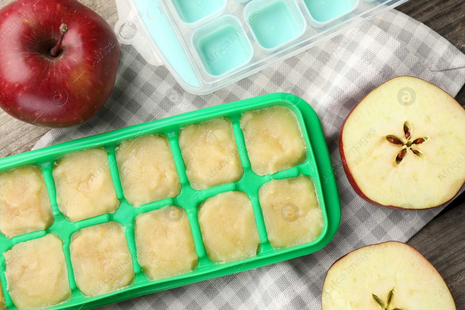 Photo of Apple puree in ice cube tray with ingredients on table, flat lay