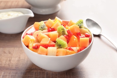 Photo of Bowl with fresh cut fruits on wooden table