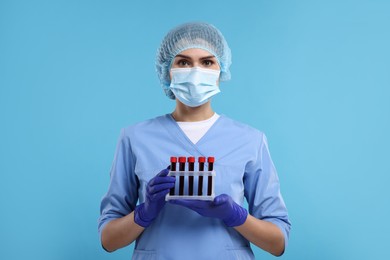 Laboratory testing. Doctor with blood samples in tubes on light blue background