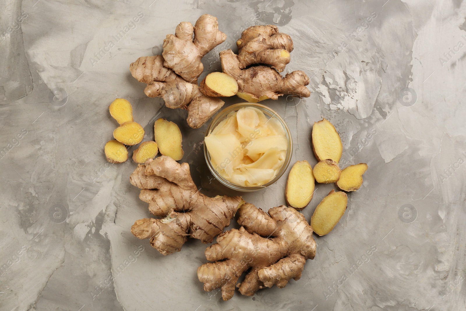 Photo of Spicy pickled ginger and root on light grey table, flat lay