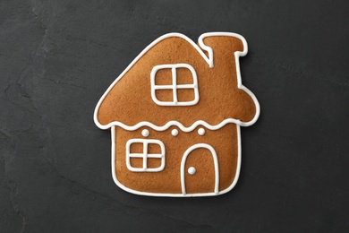 House shaped Christmas cookie on black table, top view