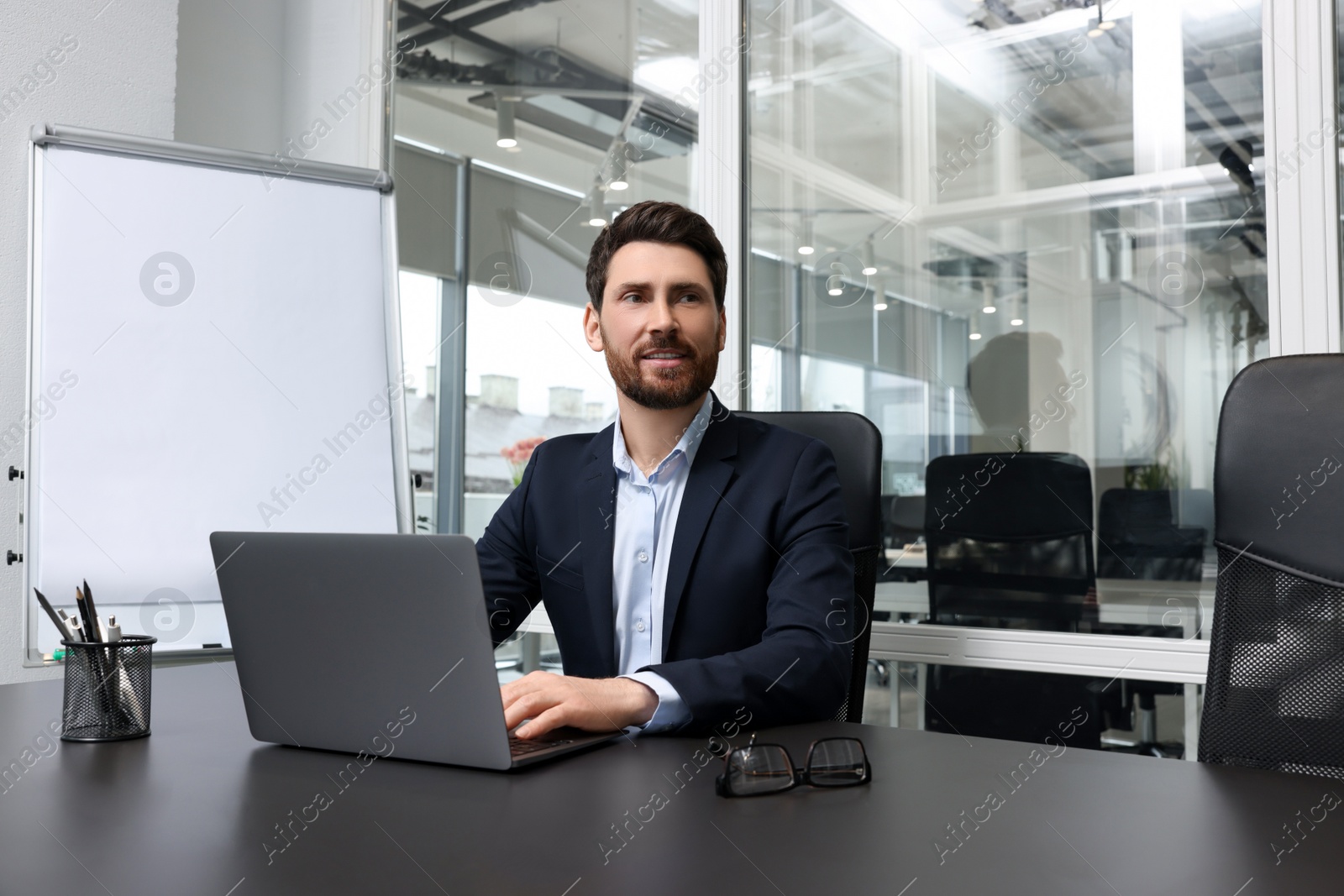 Photo of Man working on laptop at black desk in office