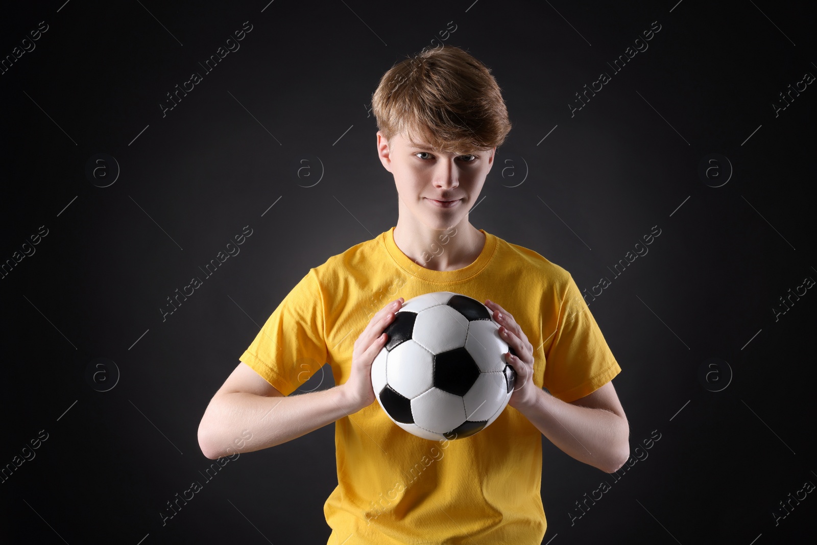 Photo of Teenage boy with soccer ball on black background