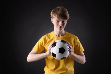 Photo of Teenage boy with soccer ball on black background