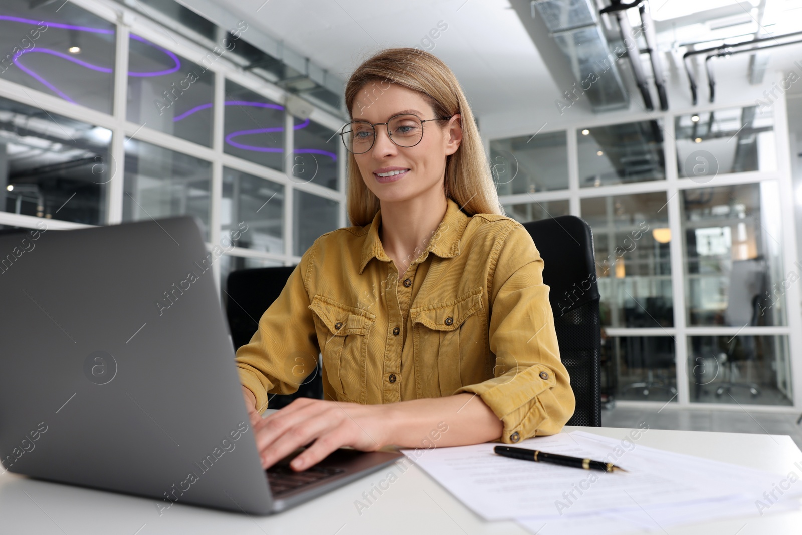 Photo of Woman working on laptop at white desk in office