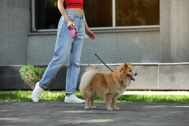 Photo of Woman with her cute dog walking on city street. closeup