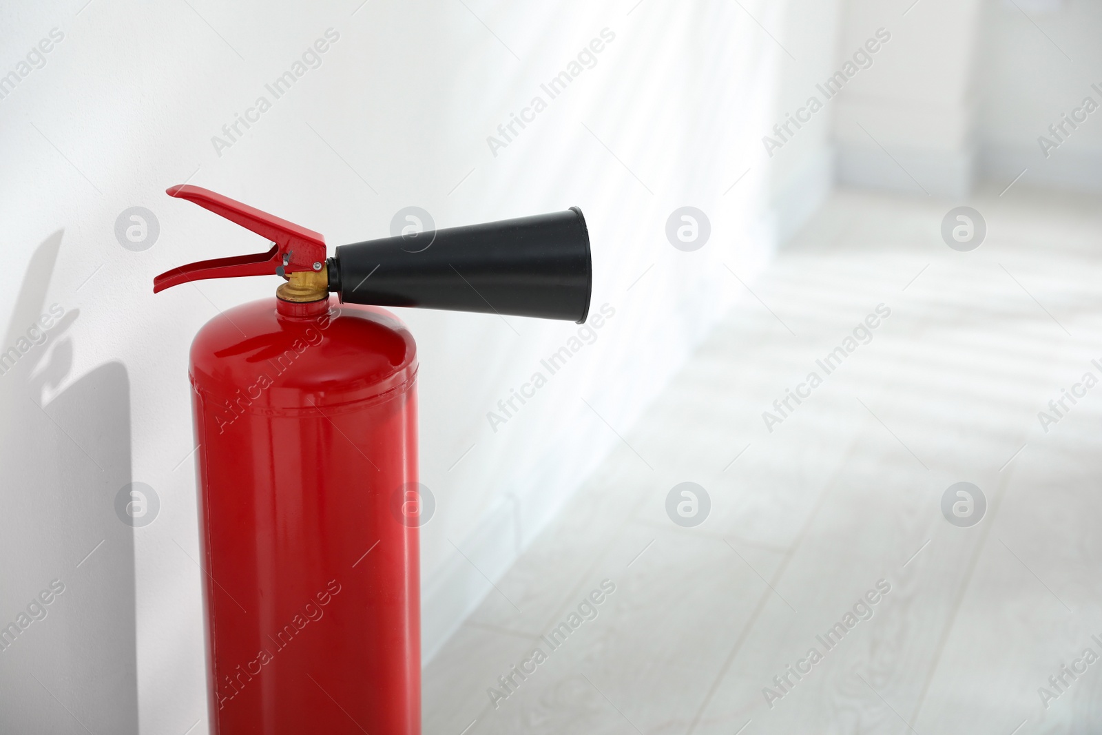 Photo of Fire extinguisher near white wall indoors. Space for text