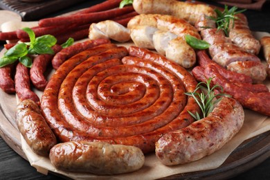 Different delicious sausages with herbs on table, closeup. Assortment of beer snacks