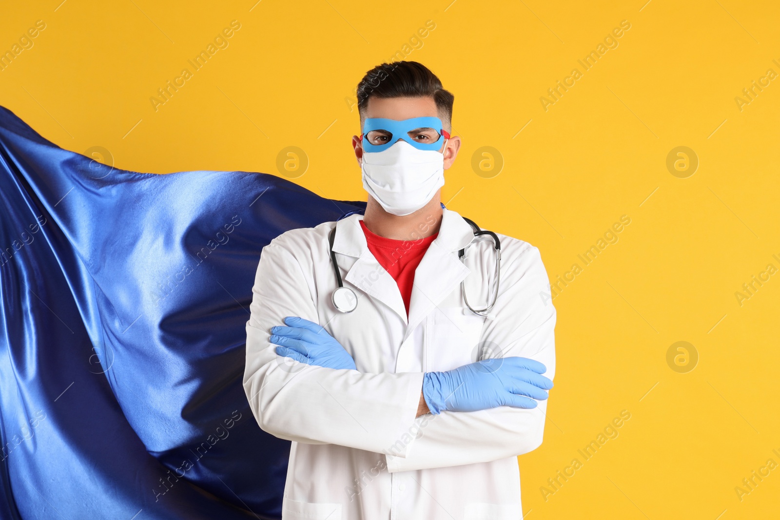 Photo of Doctor wearing face mask and cape on yellow background. Super hero power for medicine