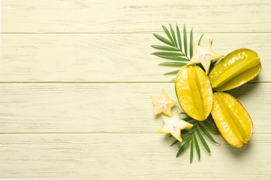 Delicious carambola fruits on yellow wooden table, flat lay. Space for text