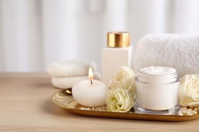 Photo of Spa composition with skin care products, flowers and candle on wooden table. Space for text