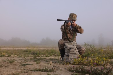 Photo of Man wearing camouflage and aiming with hunting rifle outdoors. Space for text