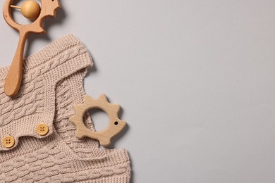 Photo of Baby accessories. Wooden rattle, teether and knitted cloth on grey background, top view. Space for text