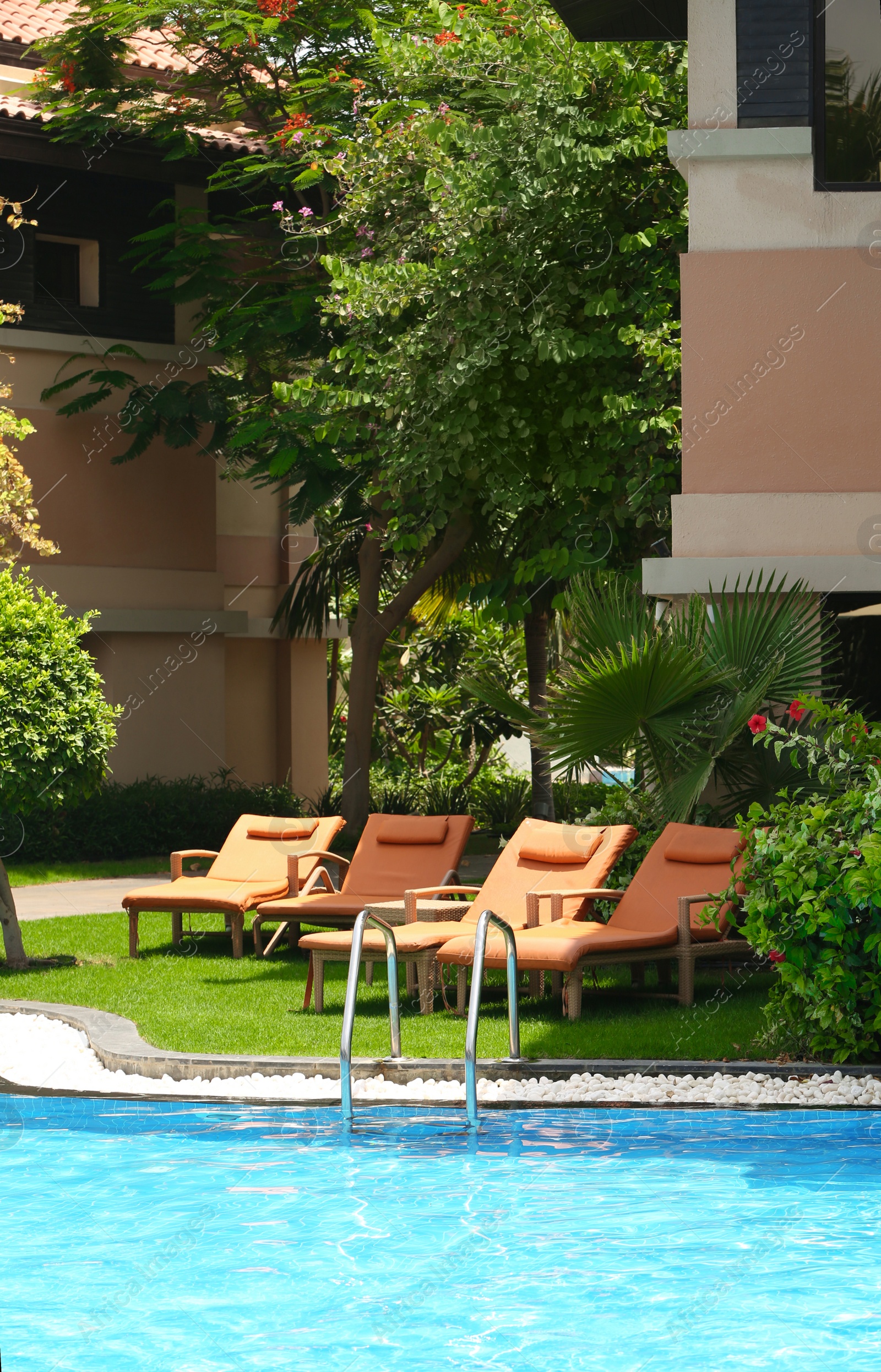 Photo of Sunbeds near modern swimming pool at resort