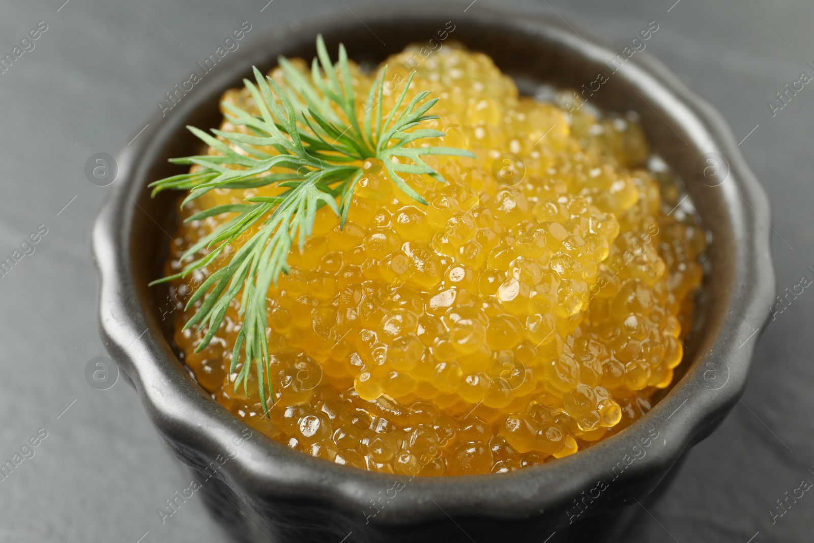 Photo of Fresh pike caviar in bowl on black table, closeup