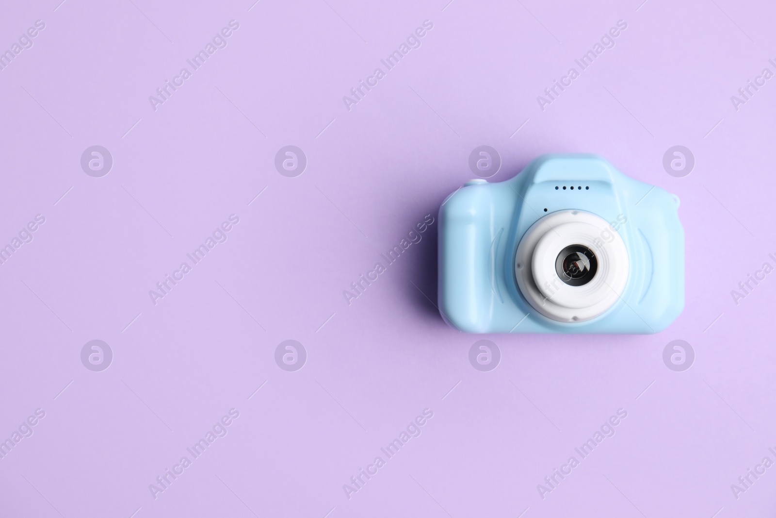 Photo of Light blue toy camera on violet background, top view with space for text. Future photographer