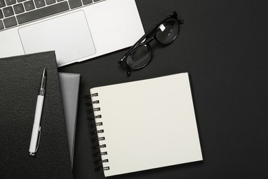 Photo of Flat lay composition with notebooks and laptop on black table