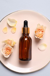 Bottle of cosmetic serum and beautiful flowers on light grey background, top view