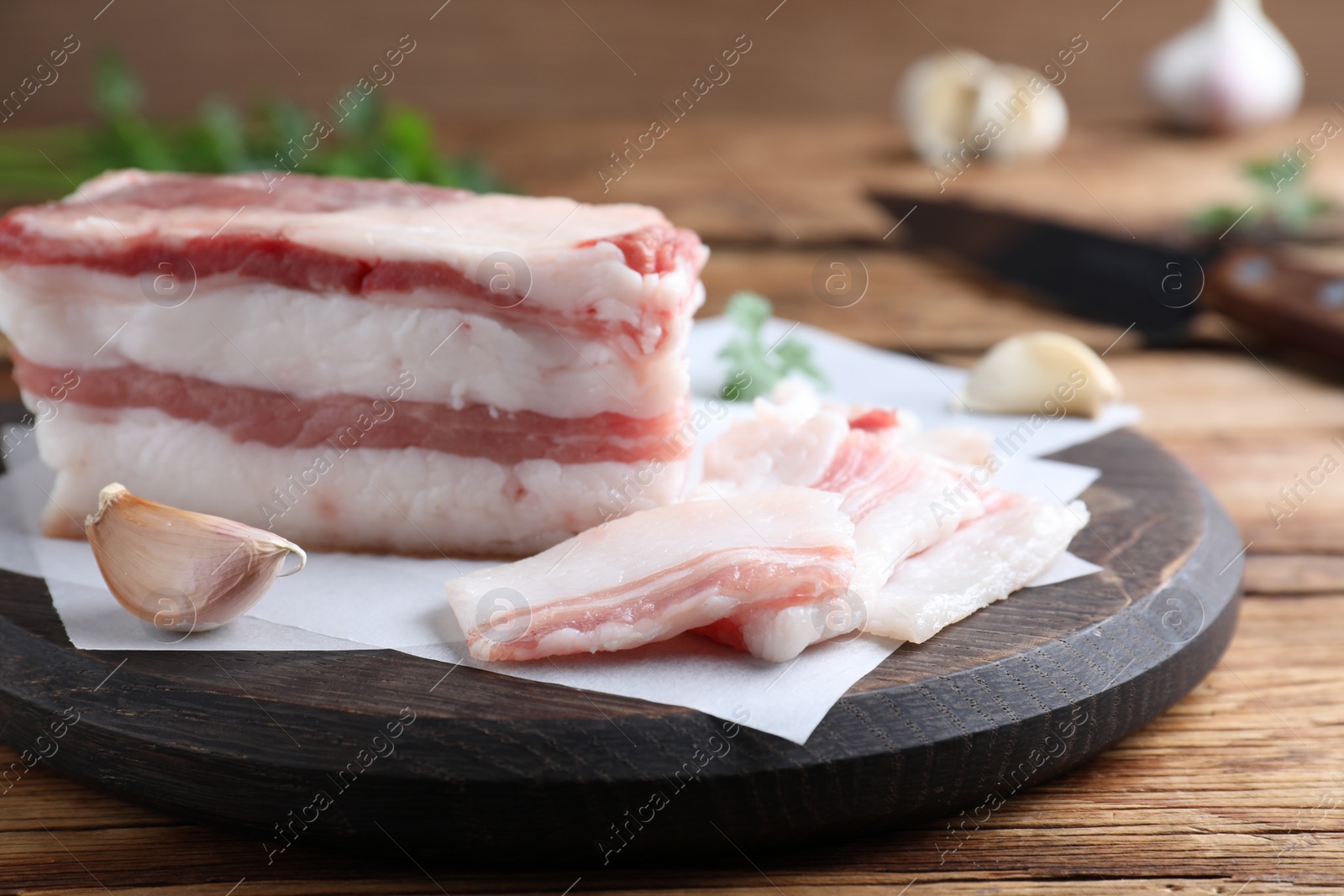 Photo of Tasty salt pork with garlic on wooden table, closeup