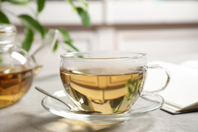 Photo of Tasty hot green tea in cup on grey table, closeup