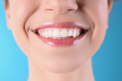 Young woman with healthy teeth and beautiful smile on color background, closeup