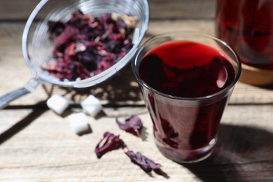 Delicious hibiscus tea in glass on wooden table, closeup. Space for text