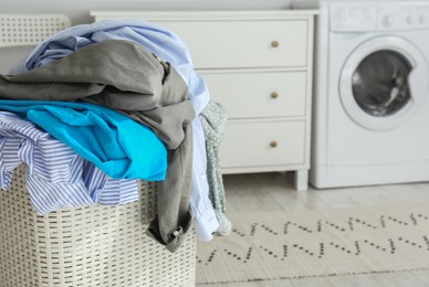 Photo of Plastic laundry basket overfilled with clothes in bathroom, closeup. Space for text