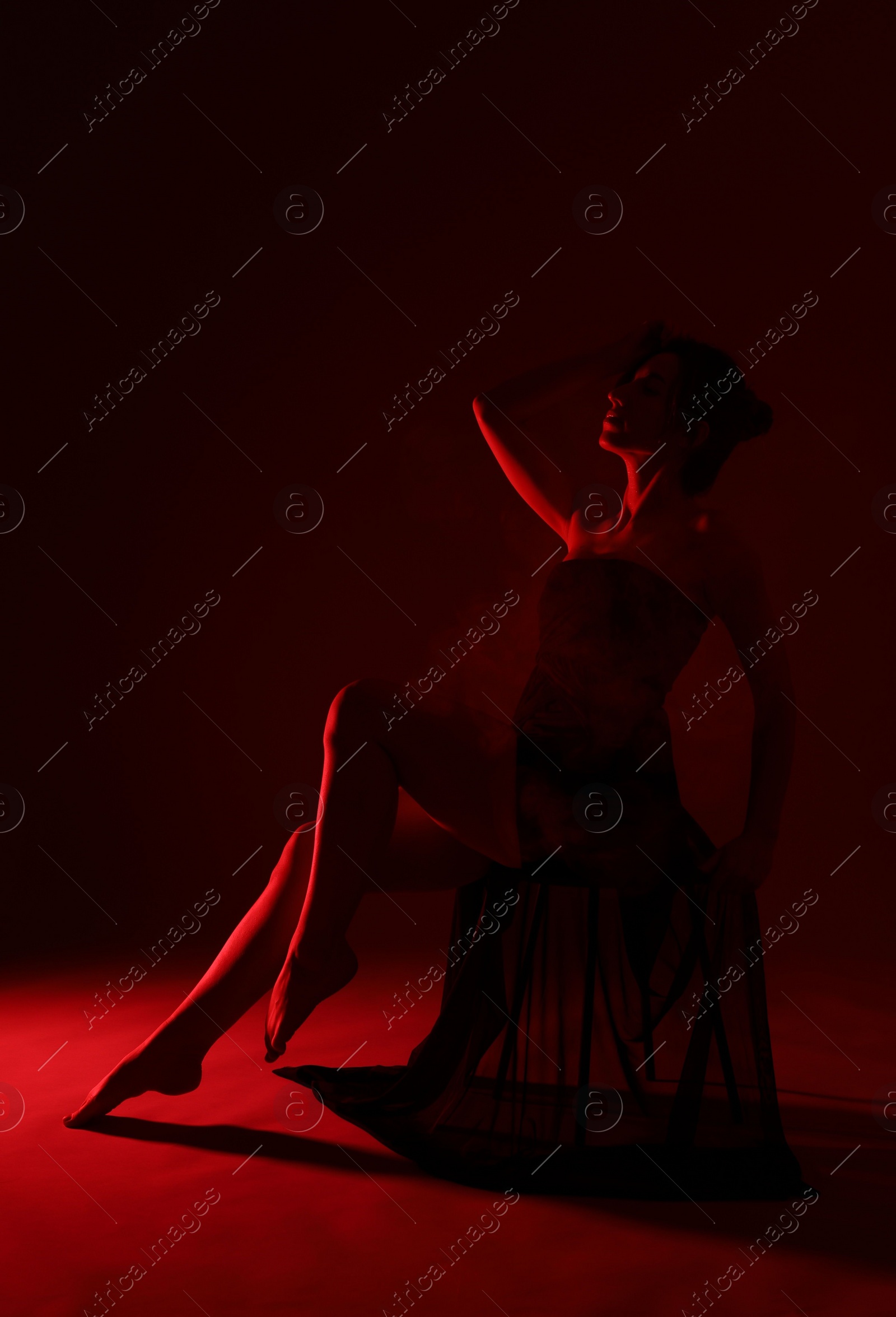 Photo of Fashionable full length portrait of attractive woman with smoke on dark red background
