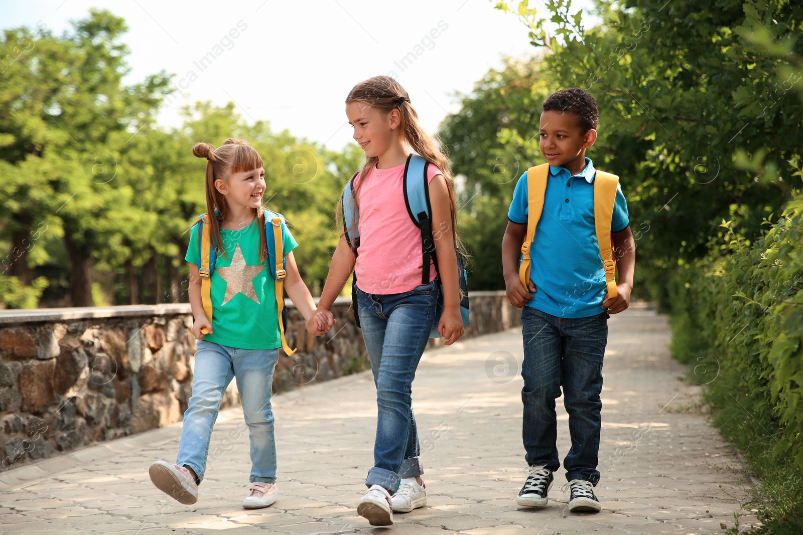 Photo of Cute little children with backpacks going to school