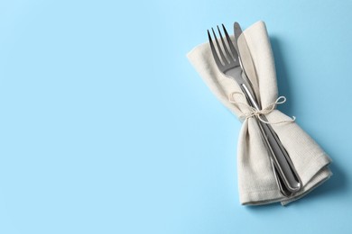 Photo of Stylish silver cutlery and napkin on light blue background, top view. Space for text